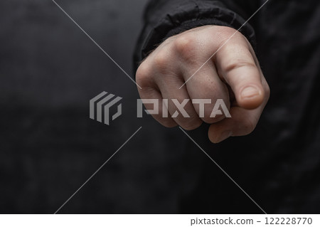 Concept of pointing finger. Close-up of a man in a sweater pointing his finger forward against on dark background. Concept of pointing finger. Close-up of a man in a sweater pointing his finger forward against on dark background. 122228770