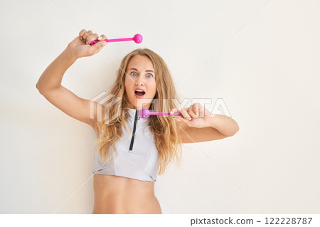 Young caucasian female playing with pink drumsticks in excitement against simple Young caucasian female playing with pink drumsticks in excitement against simple 122228787