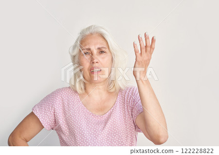 Caucasian mature female expressing frustration with hand gesture in casual polka 122228822