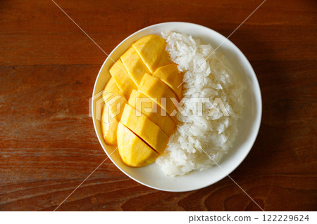 Delicious Mango sticky rice, Thai dessert from sticky rice, ripe mango, coconut milk on white plate on wooden table. 122229624