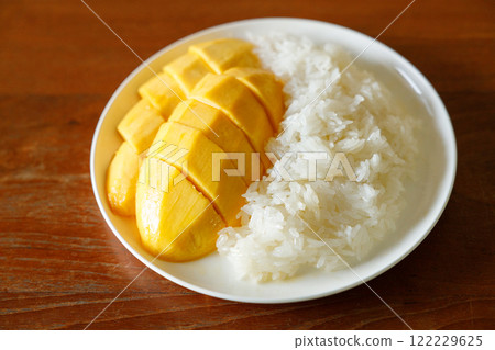 Delicious Mango sticky rice, Thai dessert from sticky rice, ripe mango, coconut milk on white plate on wooden table. 122229625