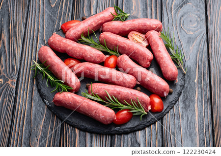 Raw beef sausages with rosemary and tomatoes photography . Top view 122230424