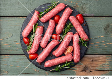 Raw beef sausages with rosemary and tomatoes photography . Top view 122230425