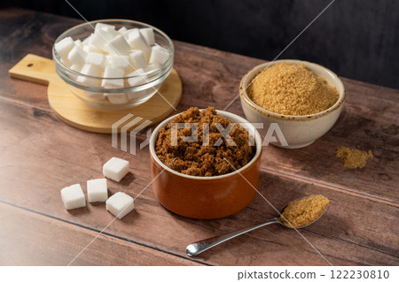 Light brown, dark brown and white sugar cubes in bowls. Different type of sugar 122230810
