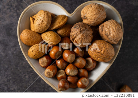 Mix of nuts in a heart shaped bowl, hazelnuts, almonds, walnuts, top view Mix of nuts in a heart shaped bowl, hazelnuts, almonds, walnuts, top view 122230891