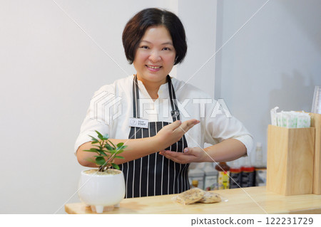 A deaf person is employed as a staff at coffee shop, pin a deaf staff sign on apron, using sign language to communicate with customers to take orders at the counter. 122231729