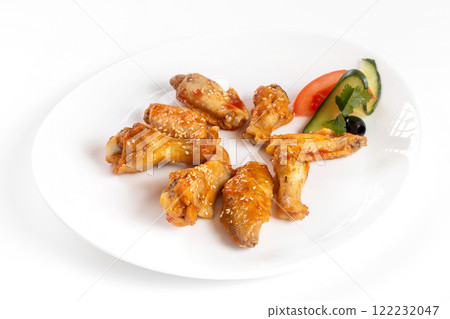 Plate of fried golden chicken wings and legs isolated at white background. 122232047