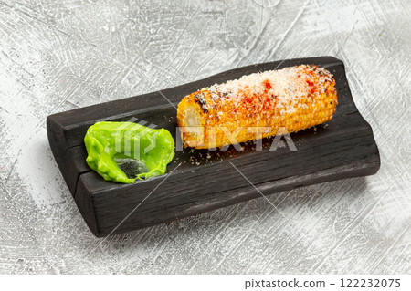 Top view image of grilled sweet corn with salt served with green sauce at wooden board at concrete table background. Top view image of grilled sweet corn with salt served with green sauce at wooden board at concrete table background. 122232075