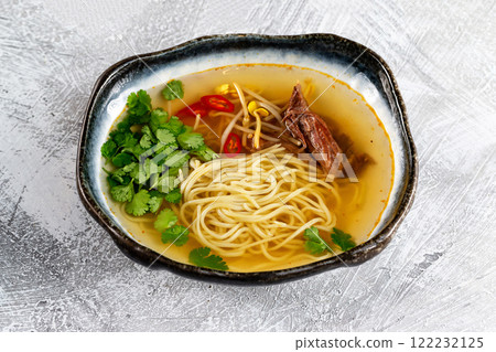 Bowl of vietnamese traditional soup pho with beef meat served at white concrete background. 122232125
