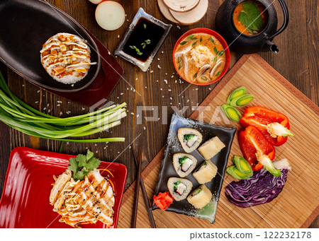 Top view flatlay japanese style business lunch including soup, salad, sushi and main meal at wooden table decorated background. 122232178