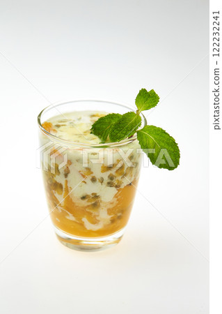 glass of healthy tropical fruit shake with mango, passion fruitc coconut milk and chia seeds decorated with mint isolated at white background. glass of healthy tropical fruit shake with mango, passion fruitc coconut milk and chia seeds decorated with mint isolated at white background. 122232241