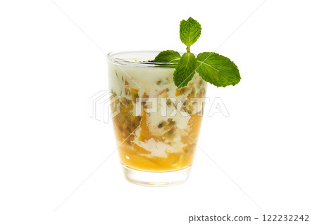 glass of healthy tropical fruit superfood shake with mango, passion fruitc coconut milk and chia seeds decorated with mint isolated at white background. Vegan diet 122232242