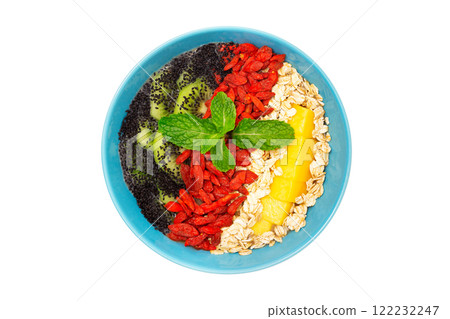 Top view image of healthy vegan detox dessert. Bowl of smoothie with kiwi, mango, oats, goji berries and chia seeds isolated at white background. 122232247