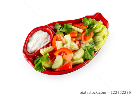 Closeup plate of fresh vegetarian vegetables salad with cucumbers and tomato served with sauce isolated at white background. 122232289
