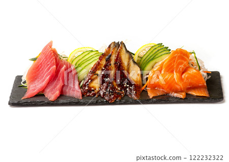 Closeup set of sashimi including tuna, salmon and eel with vegetables at black lava board isolated at white background. Closeup set of sashimi including tuna, salmon and eel with vegetables at black lava board isolated at white background. 122232322