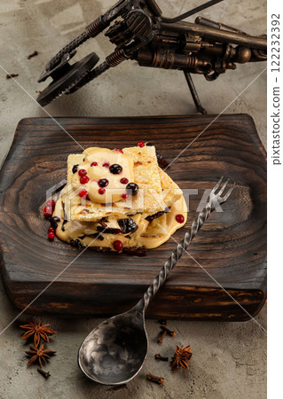 Vertical image of millefeulle with prunes and wild berries served with a spoon at wooden tray at concrete background. Vertical image of millefeulle with prunes and wild berries served with a spoon at wooden tray at concrete background. 122232392