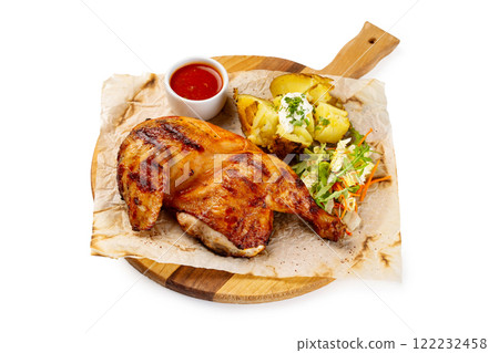 Roasted chicken legs served with potato and tomato sauce on paper at wooden tray isolated at white background. Roasted chicken legs served with potato and tomato sauce on paper at wooden tray isolated at white background. 122232458