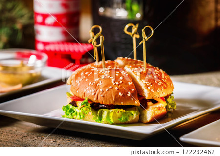 Closeup image of hamburger on white plate at Christmas style decorated wooden background. Closeup image of hamburger on white plate at Christmas style decorated wooden background. 122232462