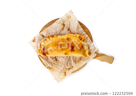 Yellow crispy khachapuri on a cooking paper at wooden board isolated at white background. 122232504