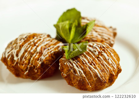 Closeup image of tasty brown muffins decorated with fresh mint leafs isolated at white background. Closeup image of tasty brown muffins decorated with fresh mint leafs isolated at white background. 122232610