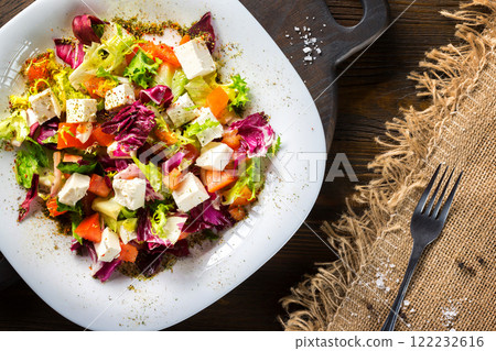 Fresh diet vegeterian salad decorated with herbs on wooden tray at table background. Fresh diet vegeterian salad decorated with herbs on wooden tray at table background. 122232616