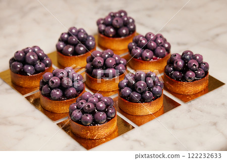 Closeup group of delicious tarts with berries served on golden paper. Restaurant sweet bakery. 122232633