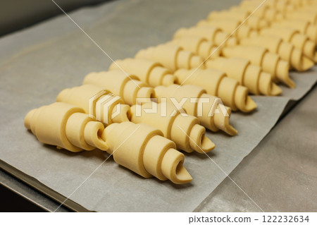 Raw croissant pastry rows at baker paper. Process of pastry making. 122232634