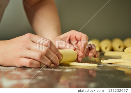 Female hand is rolling croissant dough at restaraunt kitchen. Closeup image of bakery process Female hand is rolling croissant dough at restaraunt kitchen. Closeup image of bakery process 122232637