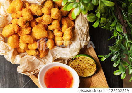 Crispy golden nuggets served with sauce at wooden board at decorated table background. 122232729