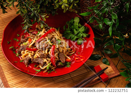 Traditional asian meal - plate of ramen noodles with beef, carrot and pepper at decorated wooden table background. Traditional asian meal - plate of ramen noodles with beef, carrot and pepper at decorated wooden table background. 122232751