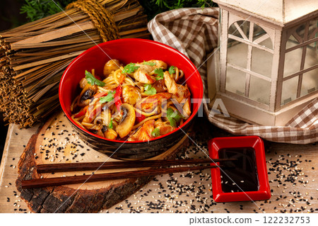 Bow of traditional asian egg noodles with chicken, vegetables and mushrooms at decorated wooden table background. Bow of traditional asian egg noodles with chicken, vegetables and mushrooms at decorated wooden table background. 122232753