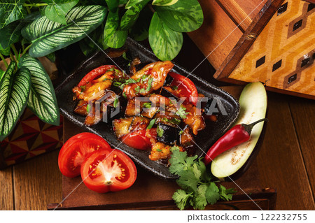 Plate of asian meal - chicken roasted with vegetables and eggplant served with chopsticks at decorated wooden table background. 122232755