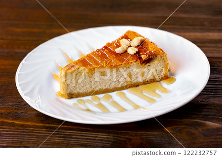 Closeup slice of cheesecake decorated with maple syrup at wooden board background. 122232757