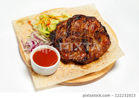 Roasted beef meat steak with sauce at a wooden board served with paper isolated at white background. 122232815