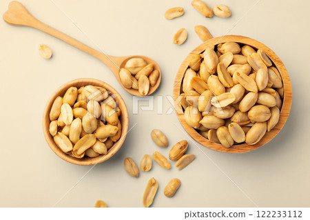 Peanuts in wooden bowls with spoon on beige background 122233112