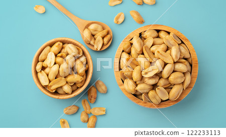 Roasted peanuts in wood bowl with spoon on blue background 122233113