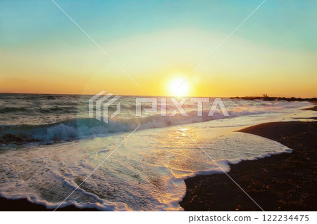 Sunrise on sandy beach against the backdrop of waves. 122234475