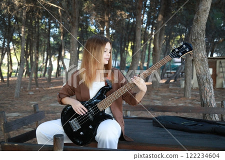 Girl Plays The Bass Instrument In The Countryside In Summer 122234604