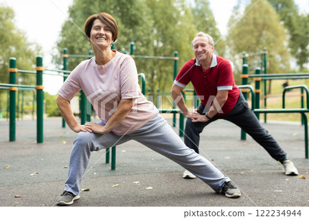 Concept of healthy lifestyle for the elderly. Family couple doing gymnastic exercises together on sports ground 122234944