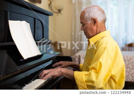Old man playing piano at home 122234948