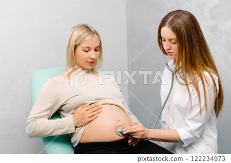 Female doctor using stethoscope examining pregnant woman in clinic. Medical exam pregnant woman 122234973