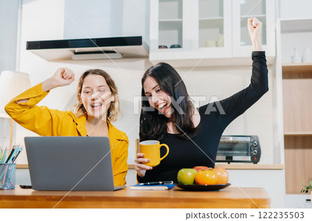 Happy smiling two woman sitting in the kitchen, feel happy successful work complete. Happy smiling two woman sitting in the kitchen, feel happy successful work complete. 122235503