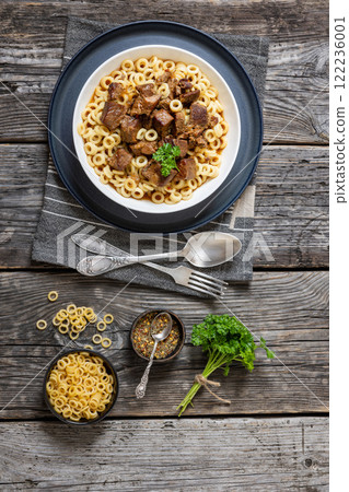 pasta rings topped with braised meat in bowl pasta rings topped with braised meat in bowl 122236001