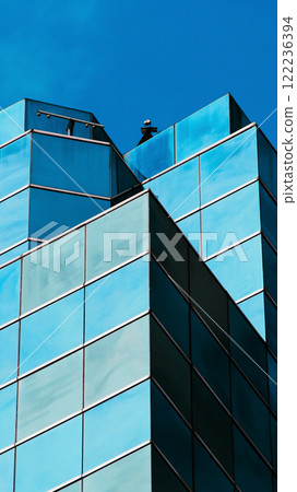 Minimalist architecture with bold lines, reflecting a vivid blue sky. ideal for modern branding or urban-themed designs. 122236394