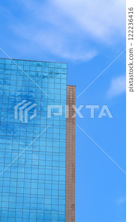 Minimalist Elegance. A sleek modern facade of blue-tinted glass reflecting soft clouds, paired with clean architectural lines, perfect for showcasing simplicity and contemporary design Minimalist Elegance. A sleek modern facade of blue-tinted glass reflecting soft clouds, paired with clean architectural lines, perfect for showcasing simplicity and contemporary design 122236416
