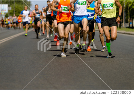 dozens runners sprint down wide city road during  competitive race. 122238000