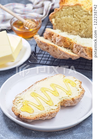 Freshly baked white Irish soda bread with butter and honey served on a plate, vertical 122238742