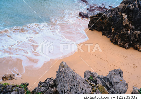 A rocky beach with a white ocean wave crashing against the rocks. A rocky beach with a white ocean wave crashing against the rocks. 122239032