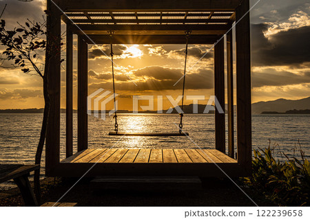 Sunset over the sea and a wooden swing 122239658
