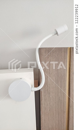 Modern white reading lamp attached to headboard in hotel room 122239912